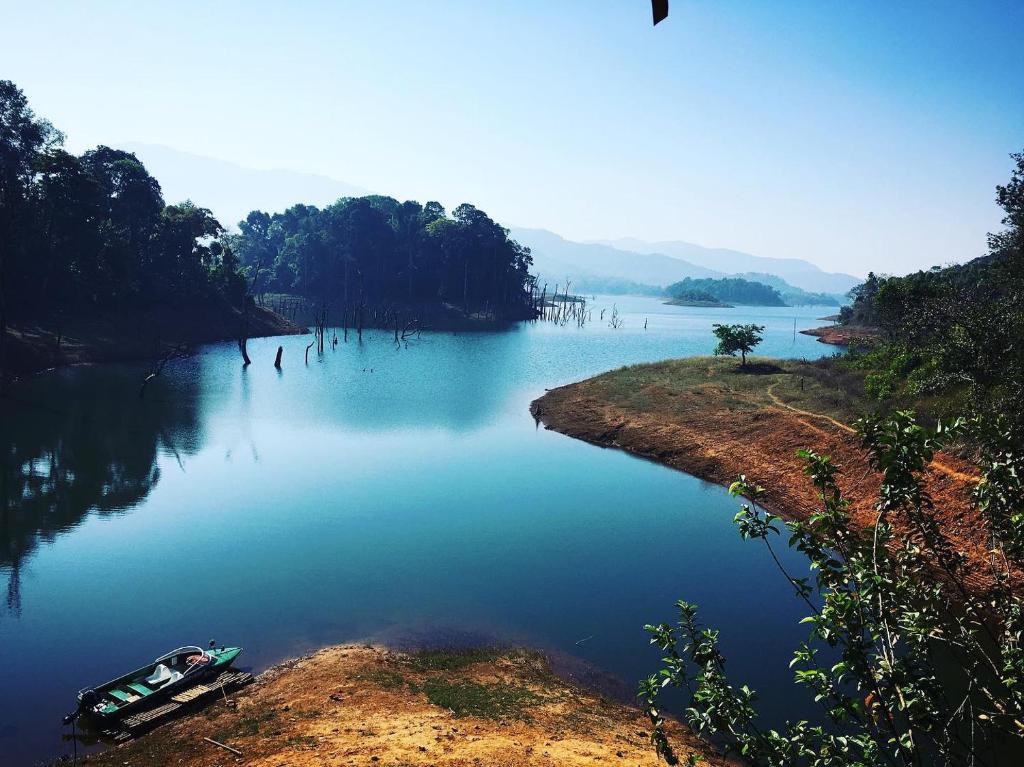 a boat on a river with trees on the shore at Silver Green Resort in Wayanad
