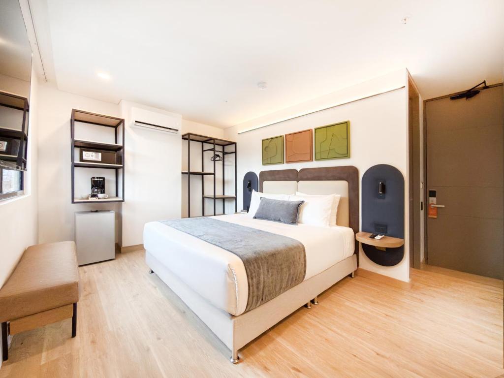 a bedroom with a large white bed and a chair at Blues Suites Laureles in Medellín