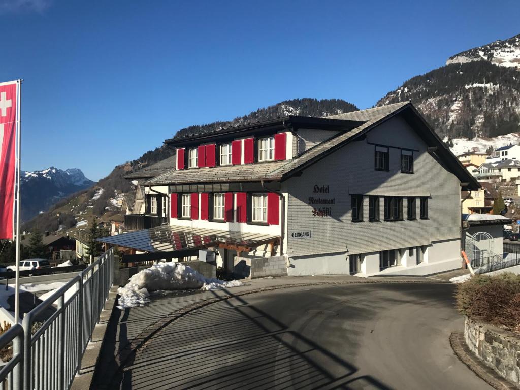 a building with red shuttered windows on a mountain at Schäfli in Amden