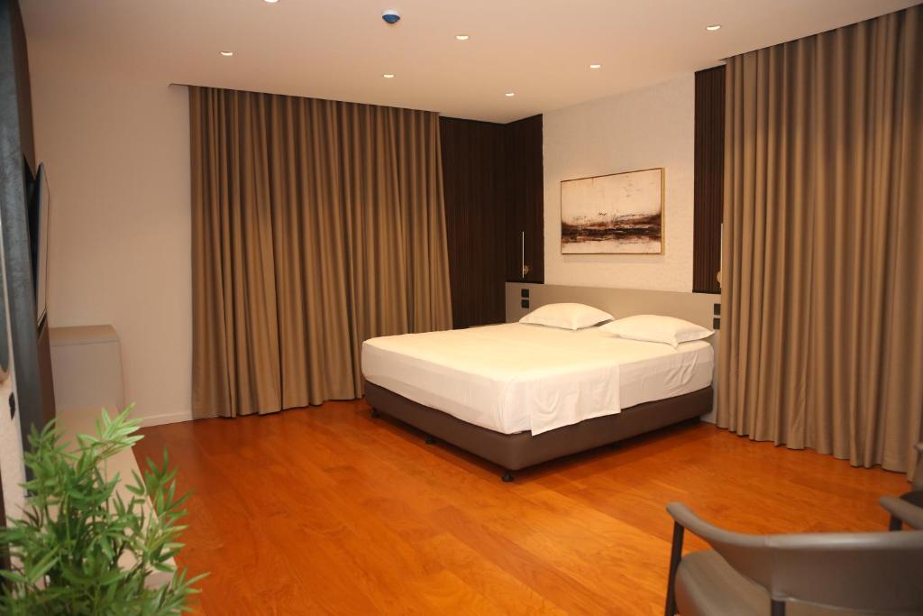 a bedroom with a bed with white sheets and curtains at Terminal Hotel in Krujë
