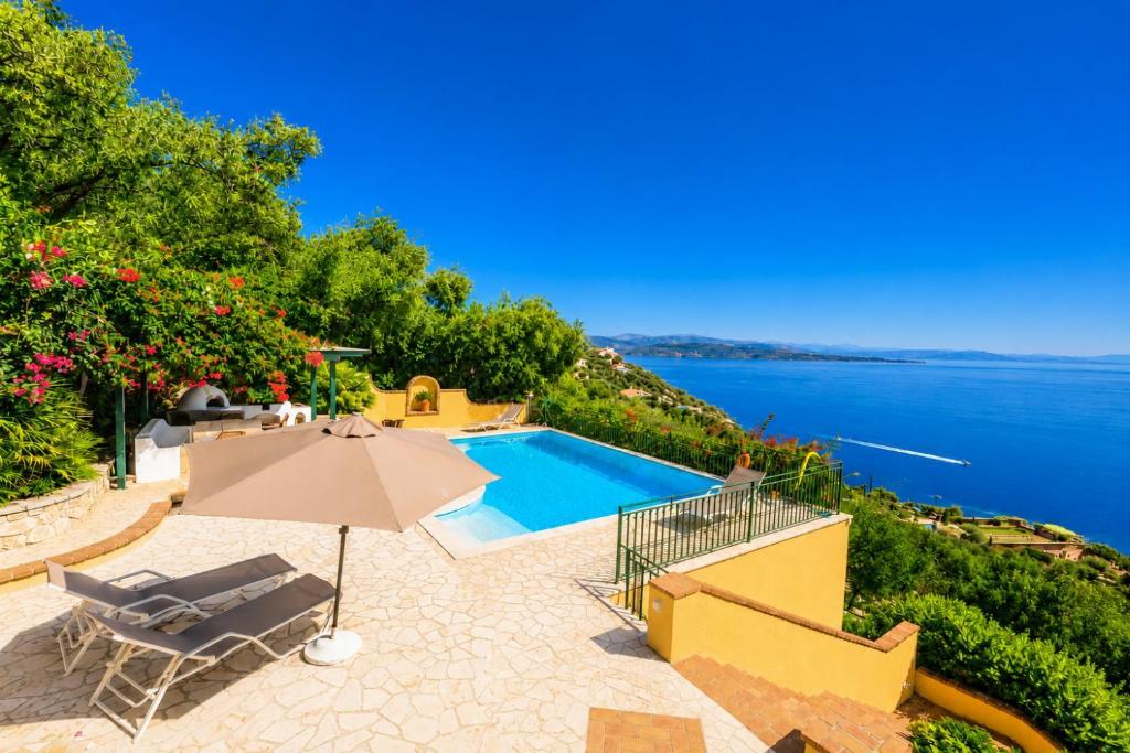 a house with a swimming pool and an umbrella at Ioannas House in Nisaki