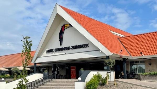a building with a red roof and a building with a flag at Van der Valk Hotel Groningen Zuidbroek in Zuidbroek