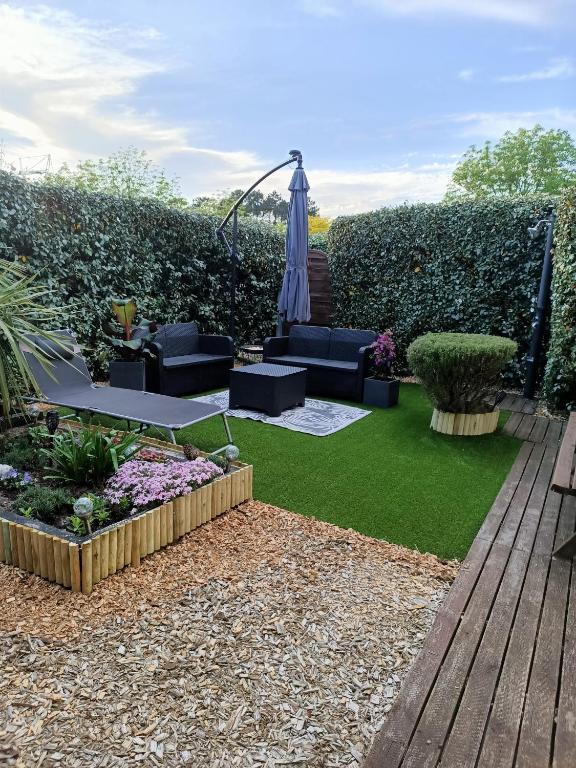 a garden with a patio with an umbrella and grass at Joli Appartement Audenge in Audenge
