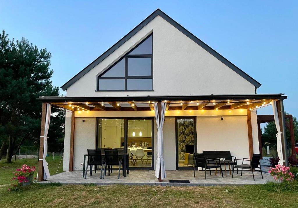 a white house with a deck with chairs and tables at Sosnowy Zakątek in Radęcin