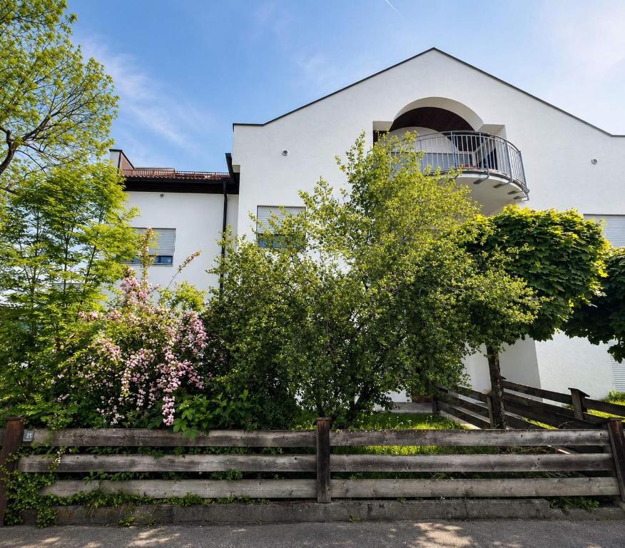 a white house with a fence in front of it at Palmen Apartment direkt in Bad Aibling in Bad Aibling