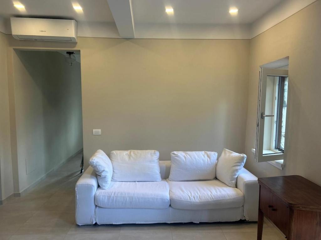 a white couch in a living room with a window at San Leo Apartment in Stia