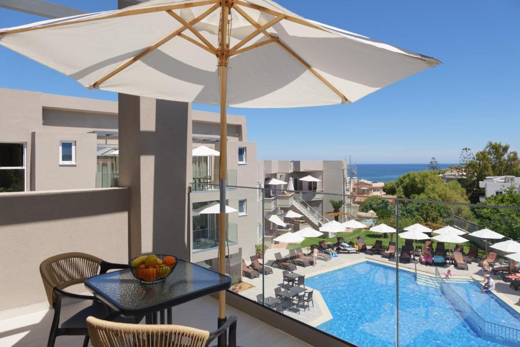a balcony with a table and an umbrella and a pool at Jechrina in Kato Daratso