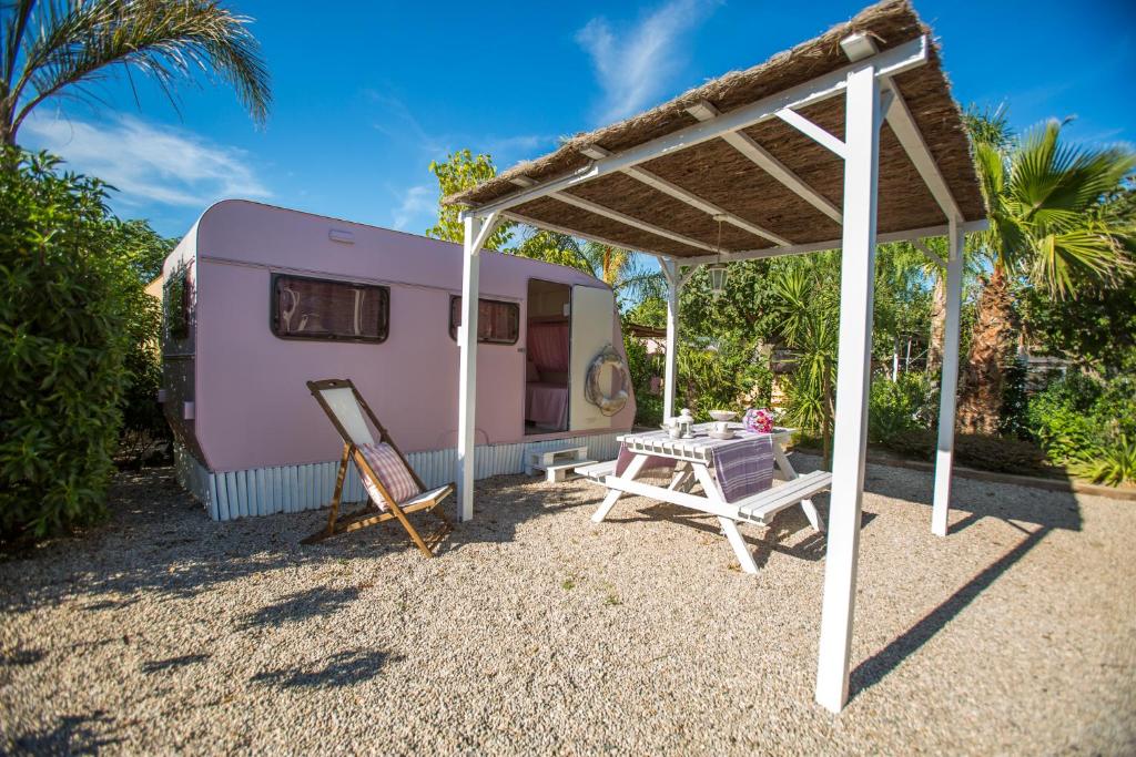 a pink caravan with a table and a tent at Camping Miramar in Miami Platja