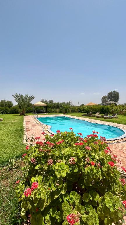 a swimming pool with flowers in a garden at Villa Riad Ambre in Douar bel Rhanodour