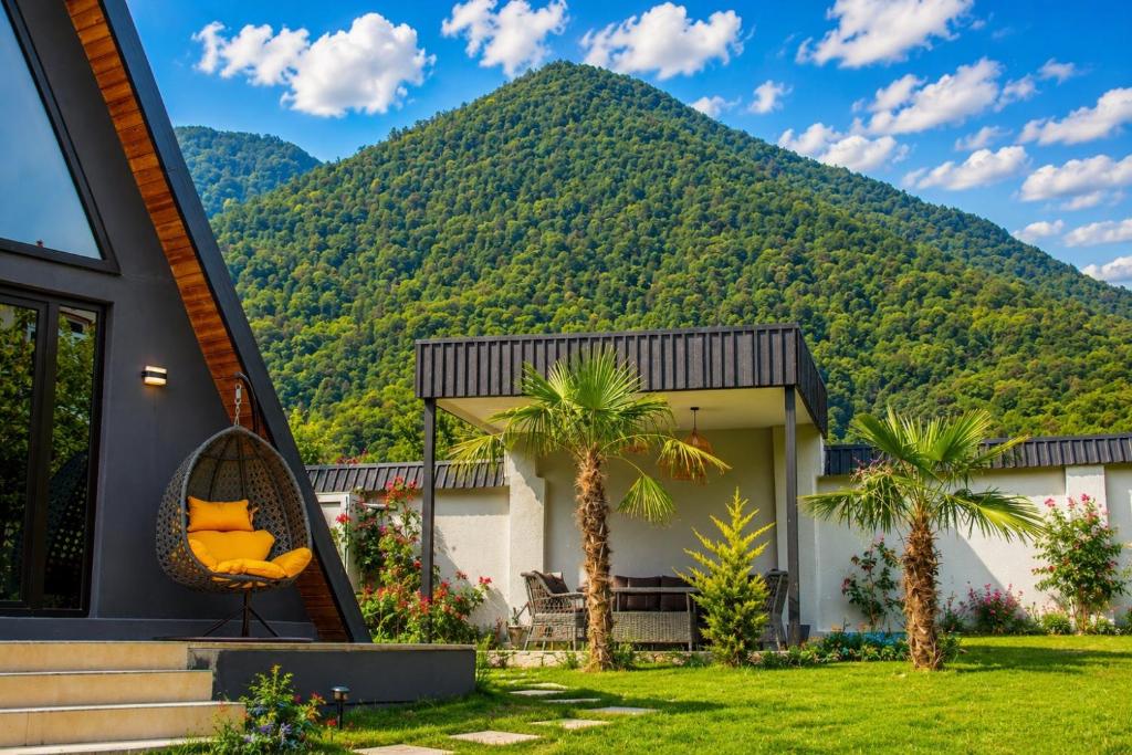 a house with palm trees in front of a mountain at Area36 Family Chalet in Gabala