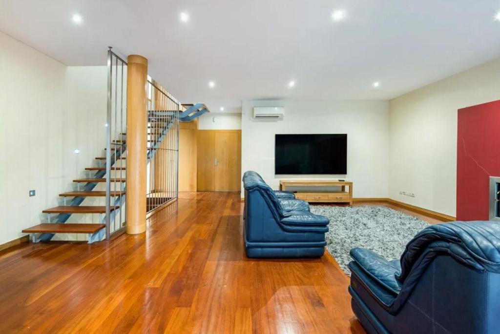 a living room with two couches and a flat screen tv at Mansion with Swimming Pool, Pool Table & GrillArea in Braga