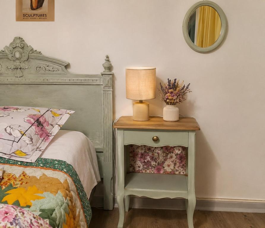 a bed with a table with a lamp on it at Le cocon in Carpentras