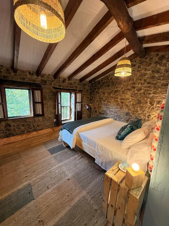 a bedroom with a bed and a stone wall at La aldea de lug in Rozagás