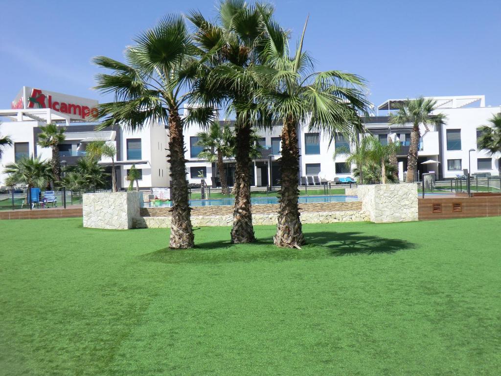 two palm trees in a park in front of a building at Casas Holiday - Oasis Beach in Playas de Orihuela