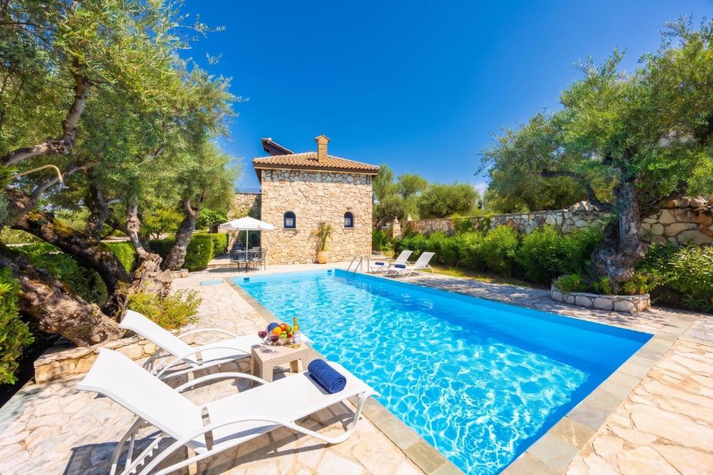 an image of a swimming pool with chairs and a house at Villa Demetra in Áyios Dhimítrios
