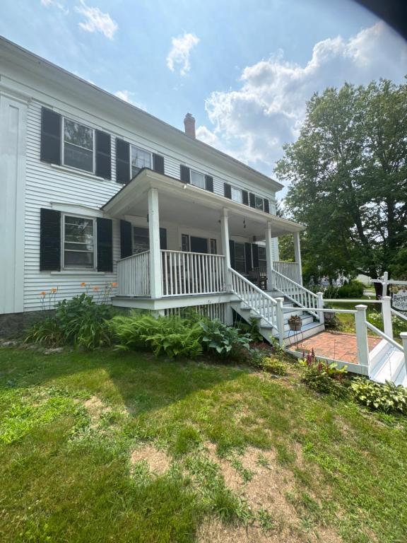 a white house with a porch and a yard at The old parsonage bed and breakfast in Kennebunkport
