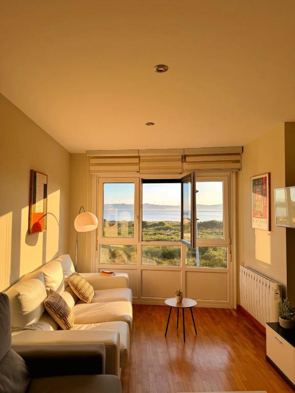 a living room with a couch and a large window at Apartamento Sandy - wifi, ascensor, vistas al Mar,Amplio y Acogedor in Laxe