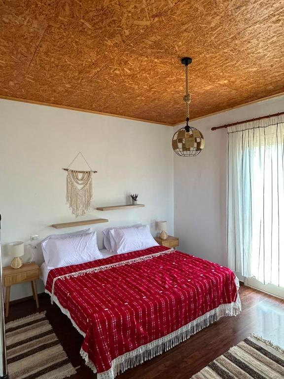 a bedroom with a bed with a red blanket at Guest House Keli in Nënshat