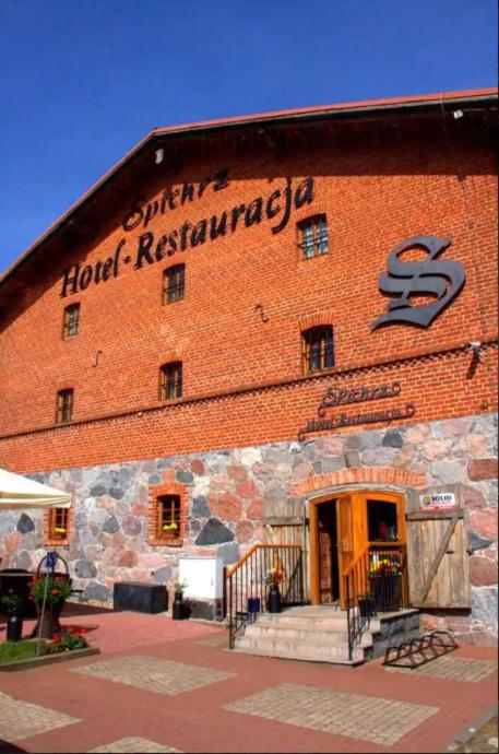 ein großes rotes Backsteingebäude mit einem Schild darauf in der Unterkunft Hotel Spichrz in Borcz