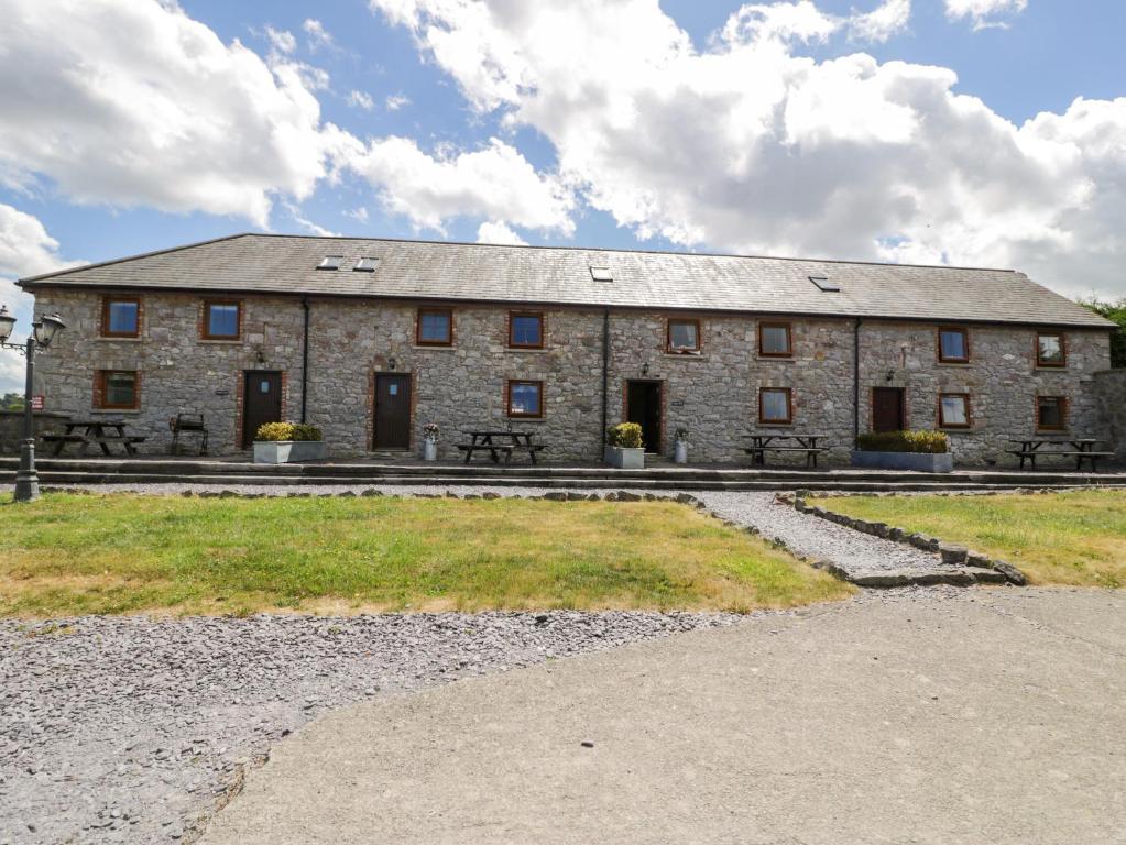 a large stone building with a table and benches in front of it at Cornel Clyd in Llanddulas