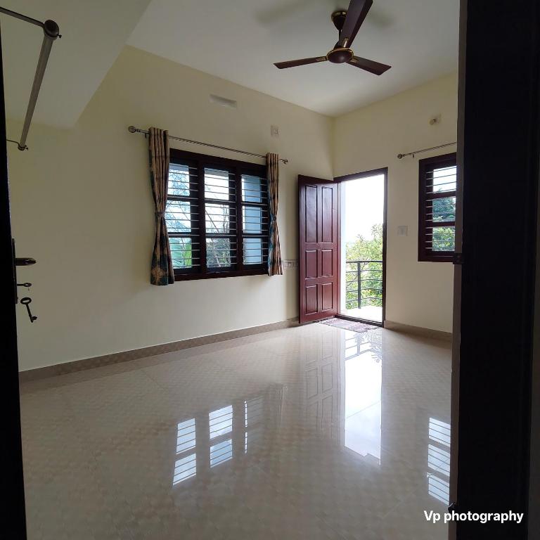 an empty room with a ceiling fan and a door at Trinity Mansion in Mangalore