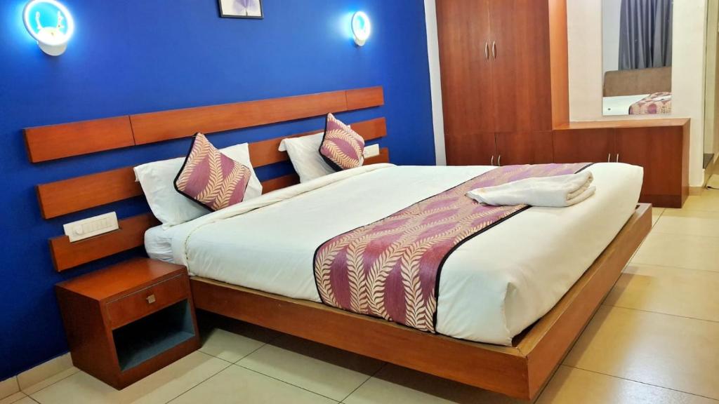 a bedroom with a large bed with a blue wall at Hotel Wayanad Gate in Wayanad