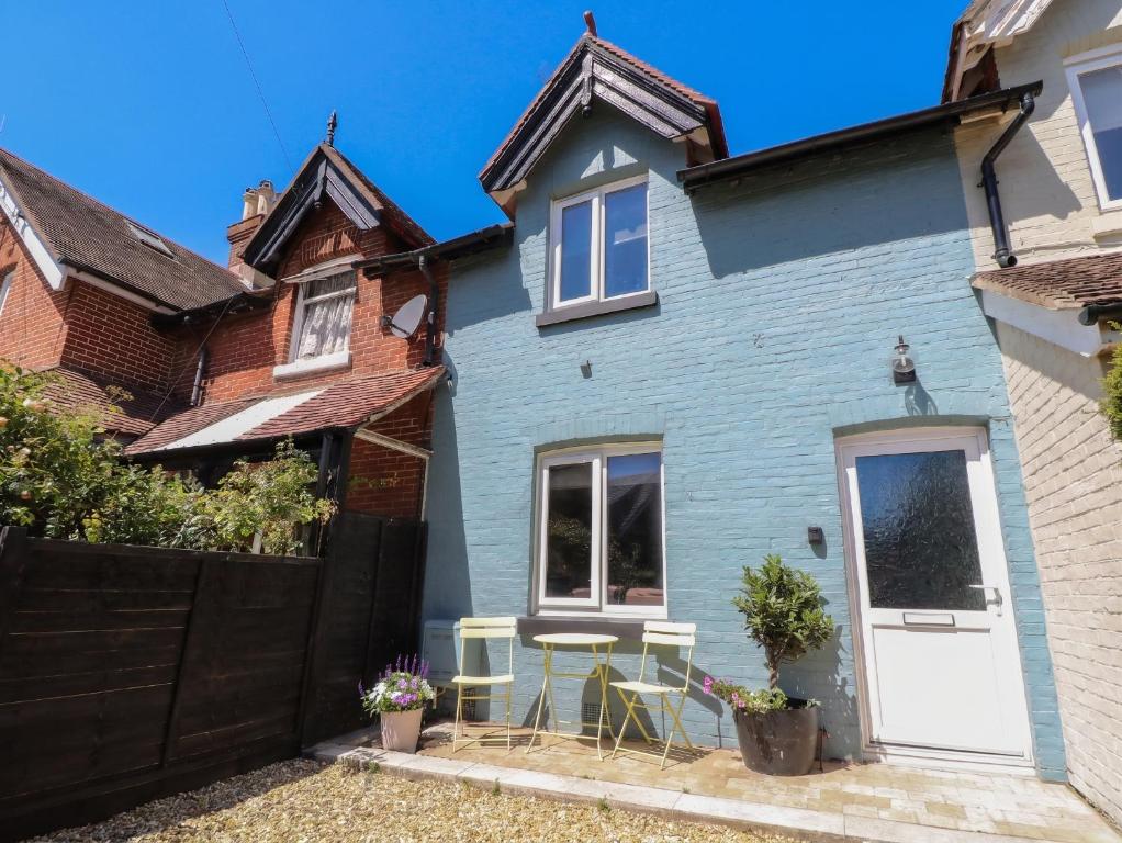a blue house with a white door and chairs at 8 Manor Villas in Totland