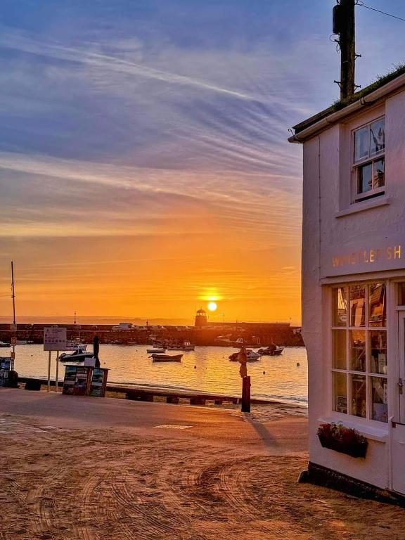 a sunset over a body of water with a building at Oak Bungalow in Carbis Bay