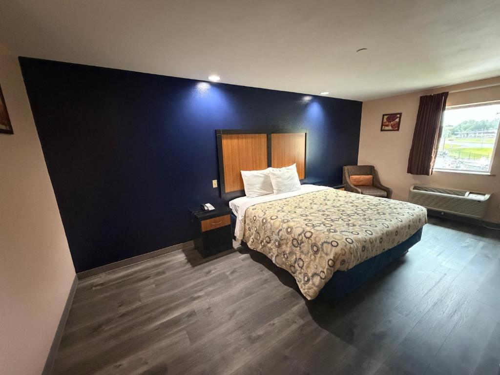 a hotel room with a bed and a chair at Paradise Inn & Suites in Baton Rouge