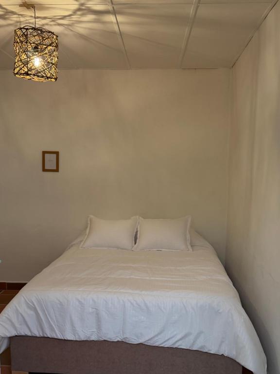 a white bed in a room with a chandelier at Casa Natus Hostal in Zapatoca