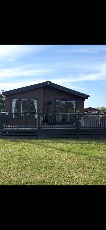a small house with a fence in a field at Atlantic Breeze, Mullacott Park in West Down