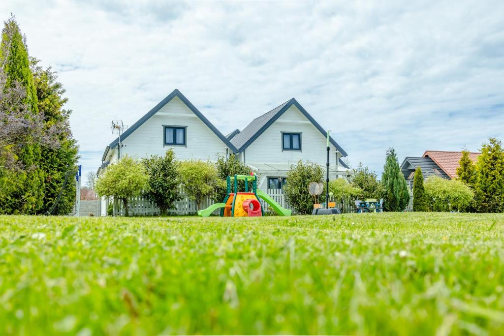 a house with a green lawn in front of it at Domki Kalipso in Sarbinowo