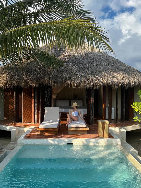 Eine Frau sitzt auf einem Stuhl neben einem Pool in der Unterkunft Aldea Mizúl - Beach Front - Adults Only in Puerto Escondido