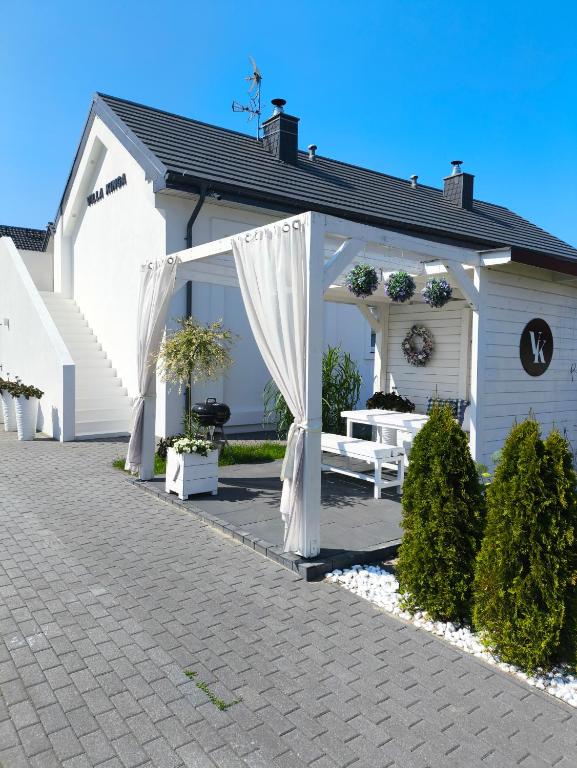 a white gazebo with a white bench in front of a house at VILLA KINGA ROWy in Rowy