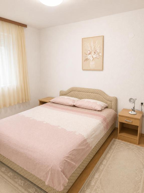 a bedroom with a large bed with a pink blanket at Apartman Suzana in Šušanj