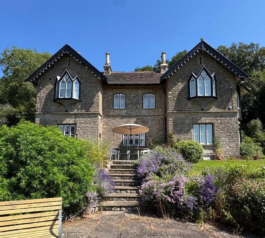 a large brick house with an umbrella in front of it at Rural Victorian Mansion with far reaching views in Wrington