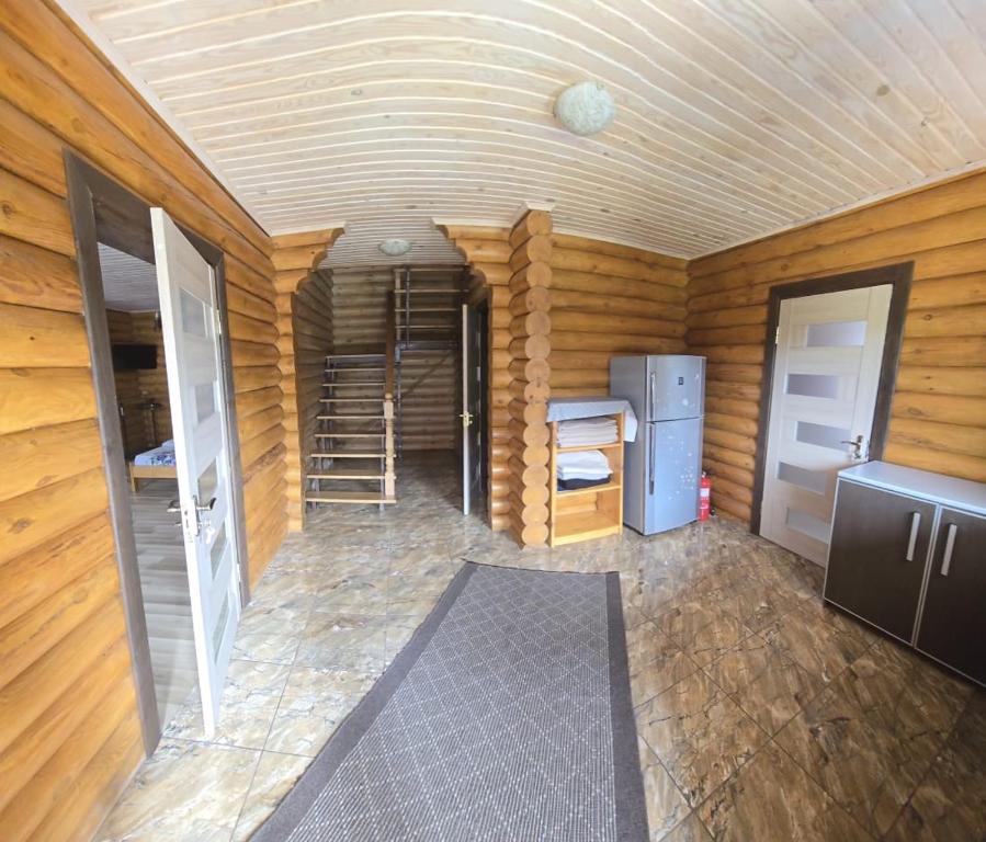 a room with wooden walls and a kitchen with a refrigerator at Релакс in Svityazʼ