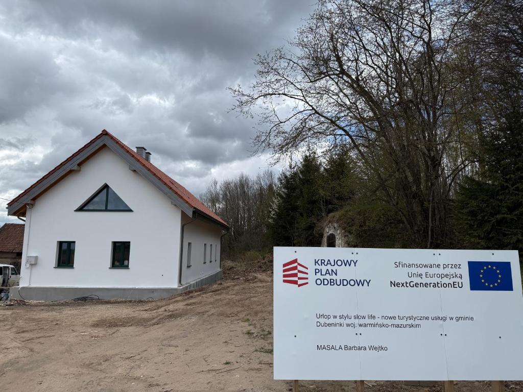 a white house with a sign in front of it at Zawiszyn 12 in Dubeninki