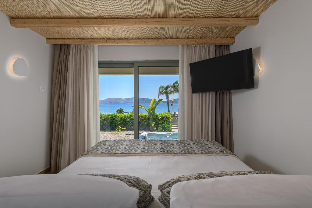a bedroom with two beds and a view of the ocean at Sirin Luxury Suites Groundfloor in Haraki