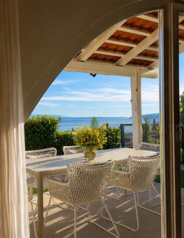 a table and chairs on a patio with a view of the ocean at Vila Ester - apartman Lovrana in Lovran
