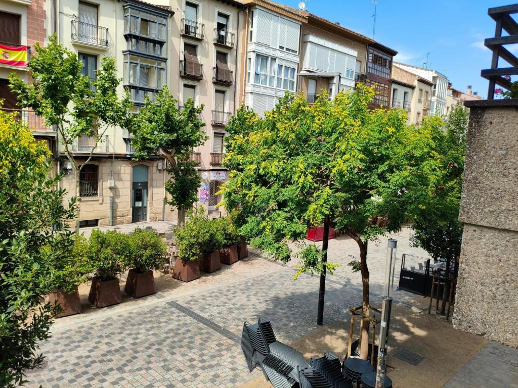 a courtyard with trees and benches in front of buildings at A un paso de Laurel Estudio con balcón in Logroño