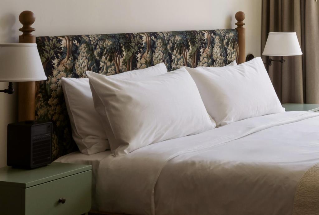 a bed with white sheets and pillows in a hotel room at The Nickel Hotel in Charleston