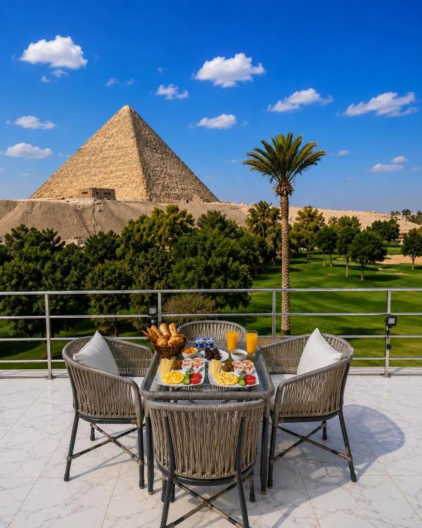 a table with food and a pyramid in the background at Glow Pyramids View Hotel in Cairo