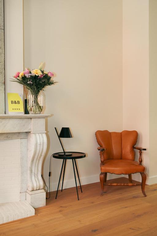 a living room with a chair and a vase of flowers at B&B Inn Between in Ghent