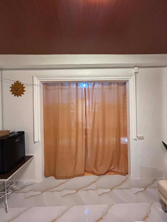 a room with a window with a curtain and a tv at Tiny house studio near SM City Daet in Daet