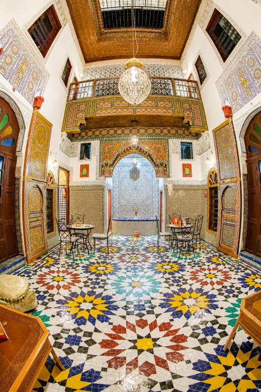 a large room with a mosaic floor with tables and chairs at Riad Chada Fez in Fez