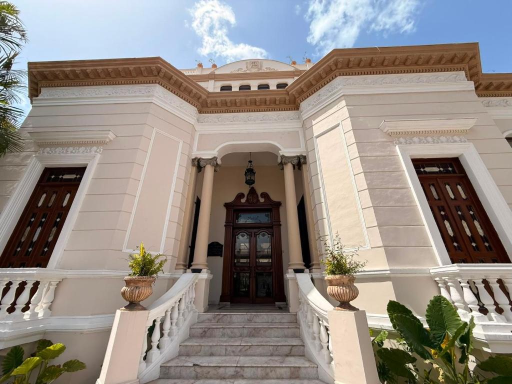 a large white building with stairs and a wooden door at Hotel Residencial in Mérida