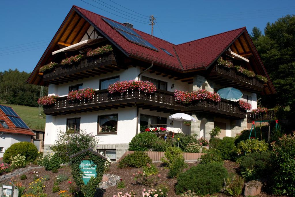 Una casa con techo rojo y flores. en Gästehaus Cornelia, en Wildensee