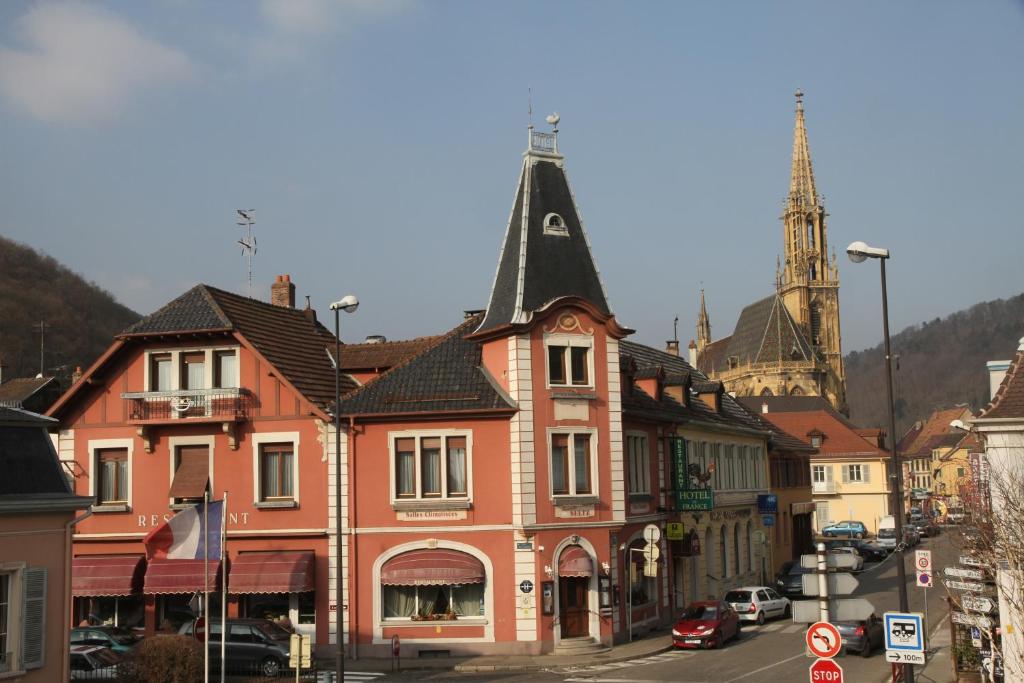 a street in a town with a church and a tower at Hôtel De France in Thann