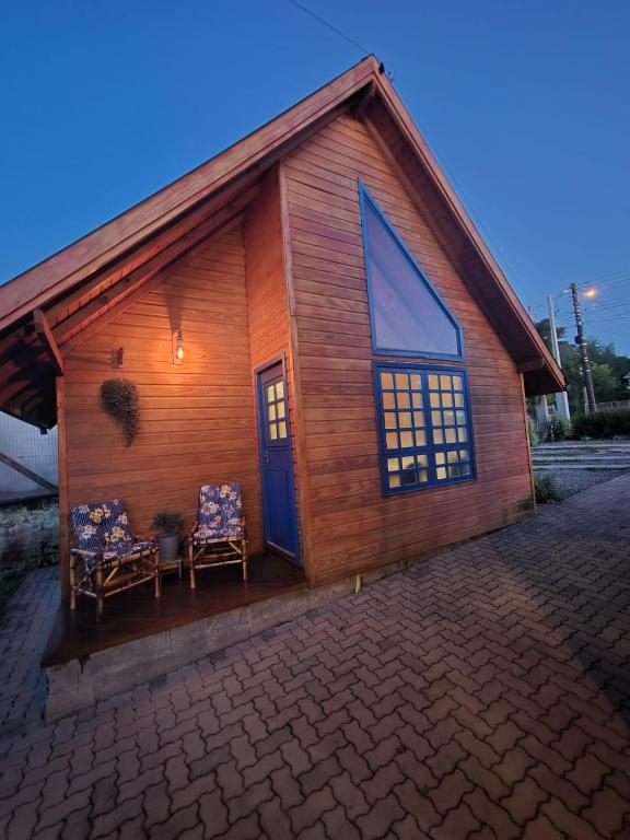 a small wooden house with two chairs on the porch at Cabanas Laura in São Francisco de Paula